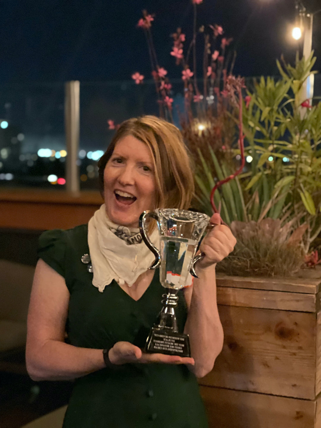 Green Bee founder Bridget May holding a first-place crystal and silver trophy for Brightening Eye Cream