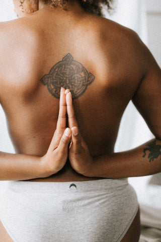 photo of the back of a sitting woman in yoga pose with hands pressing together behind her back - large mandala tattoo by huha-inc-2kZKaD0nTgA-unsplash_2_480x480